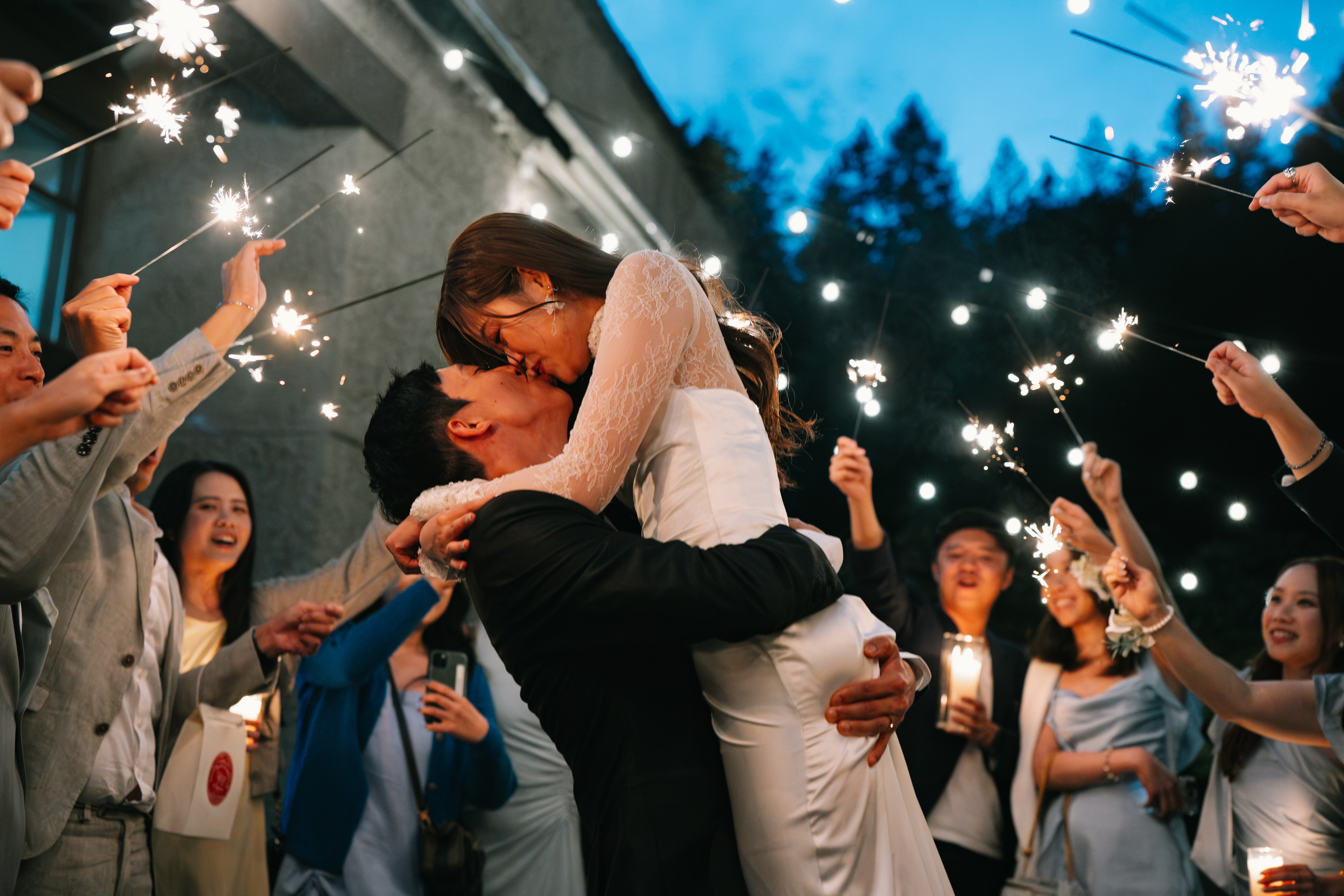 A sparkler kiss surrounded by wedding guests at Furry Creek