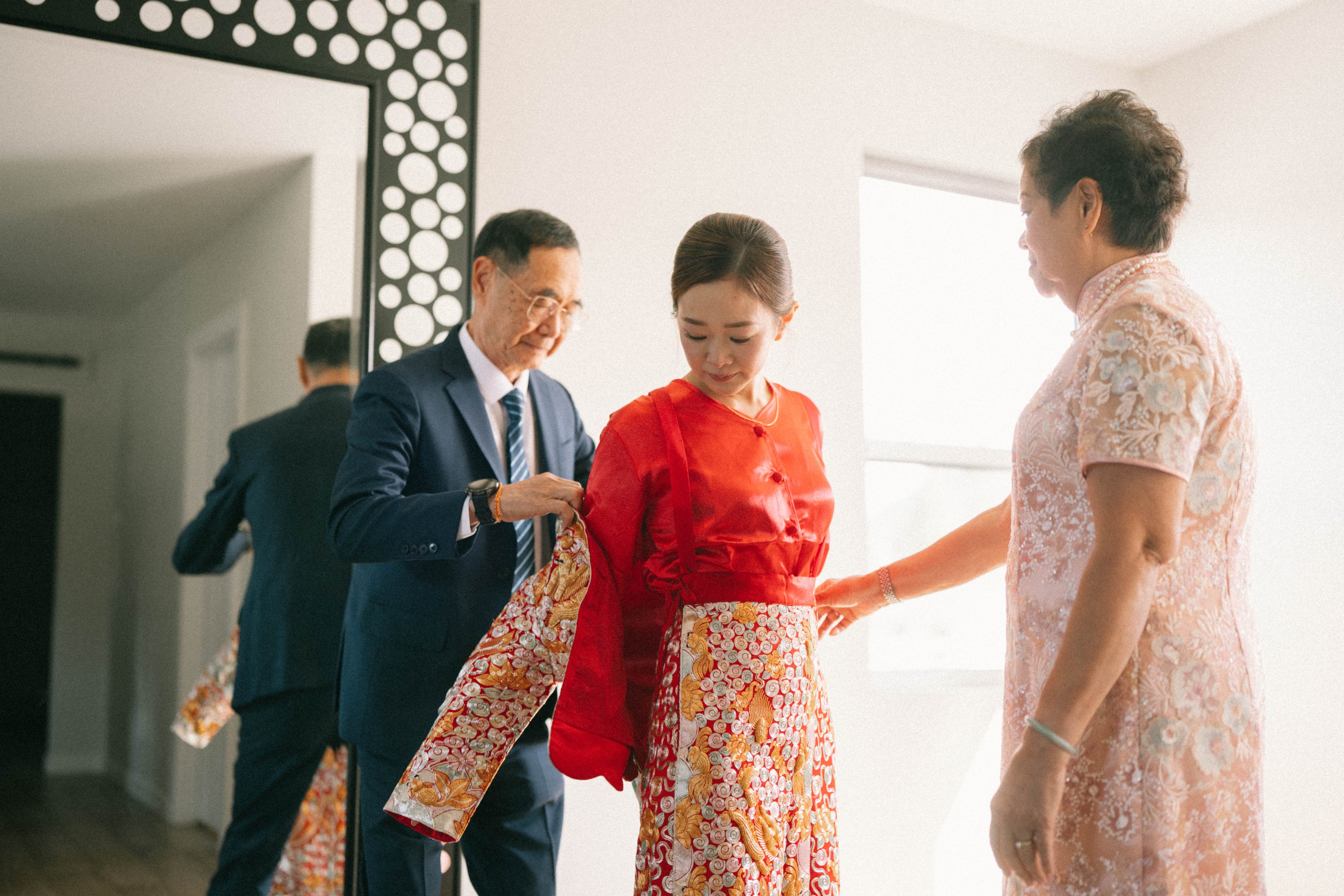 Family helping a bride prepare in traditional red wedding attire