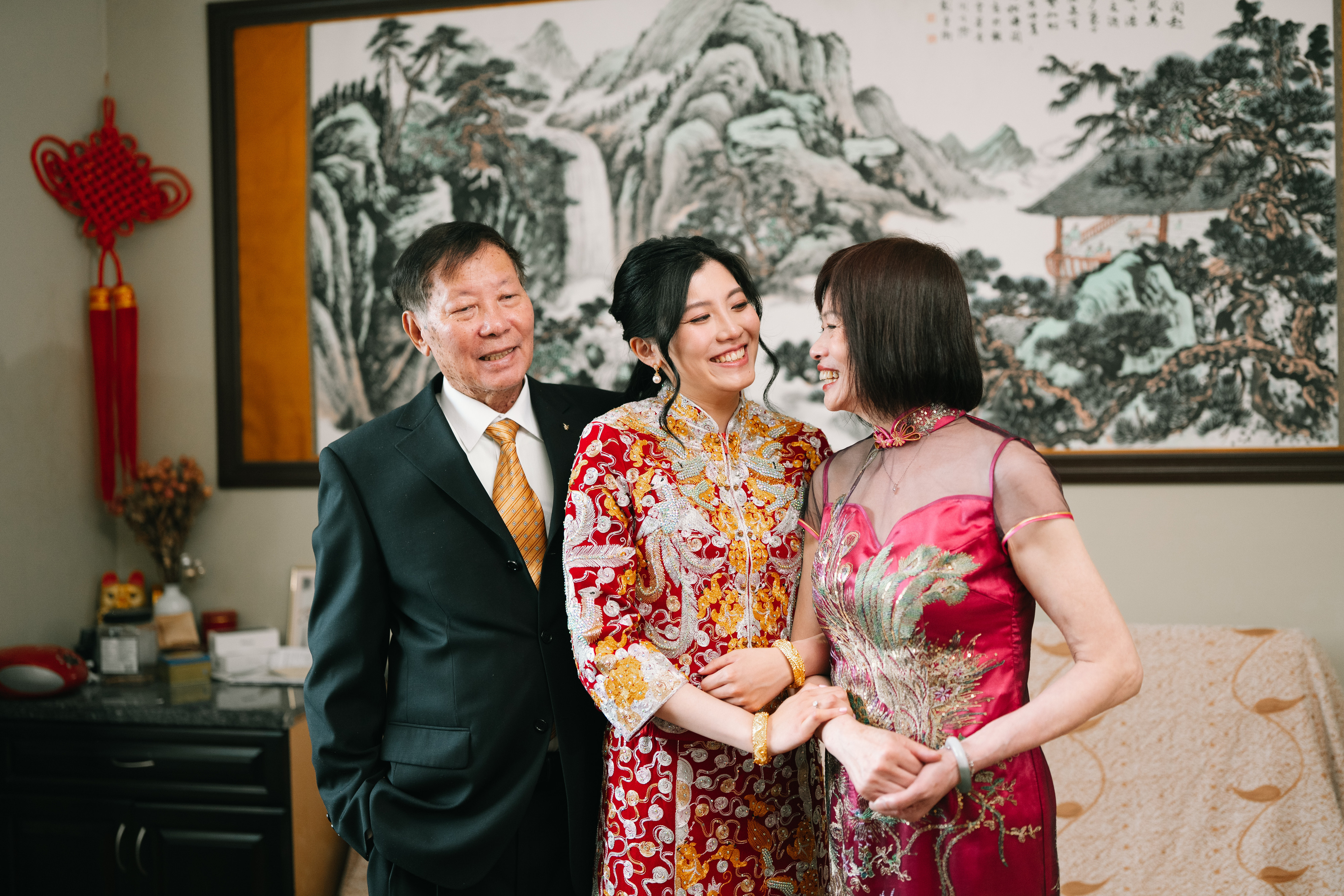 Bride in traditional red wedding attire smiling with family at Mayfair Lakes